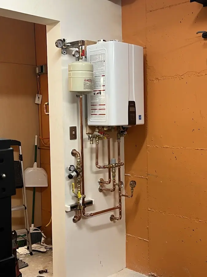 Plumbing technician inspecting water heater connections in Torrington